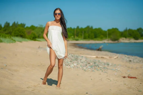 young slender woman by the sea posing in clothes