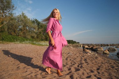 Deniz kenarındaki genç, narin kadın. Kıyafetler içinde poz veriyor.