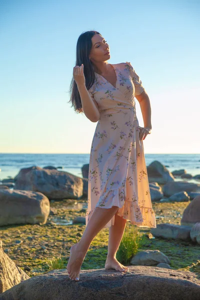 young slender woman by the sea posing in clothes