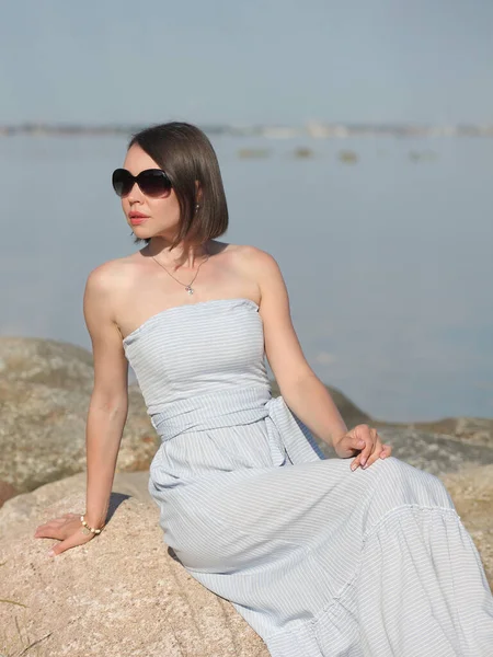 young slender woman by the sea posing in clothes