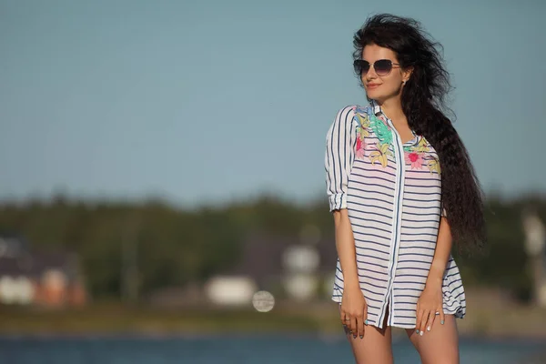 young slender woman by the sea posing in clothes