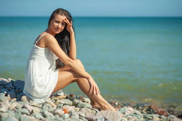 young slender woman by the sea posing in clothes