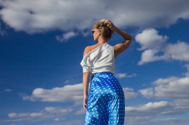 Deniz kenarındaki genç, narin kadın. Kıyafetler içinde poz veriyor.