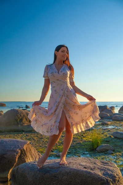 young slender woman by the sea posing in clothes