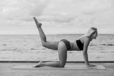 Genç bir kadın vahşi bir plajda yoga yapıyor.