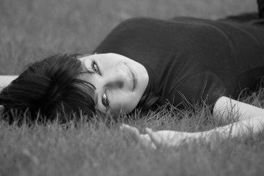 Genç, güzel, kısa saçlı esmer kadın merdivenlerde oturuyor.