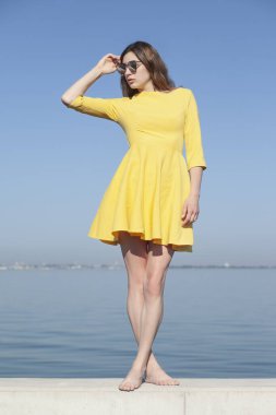 Deniz kenarındaki genç, narin kadın. Kıyafetler içinde poz veriyor.