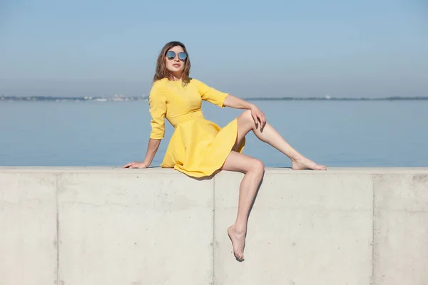 young slender woman by the sea posing in clothes