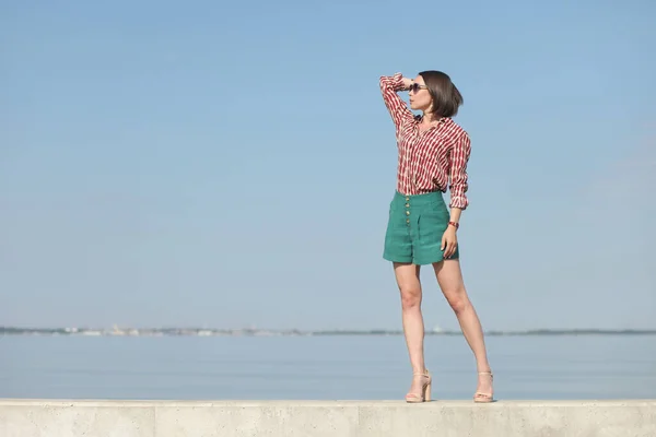 young slender woman by the sea posing in clothes