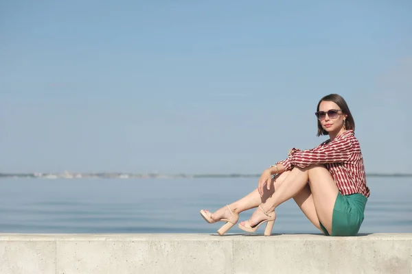 young slender woman by the sea posing in clothes