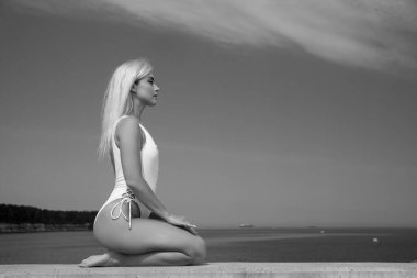 young beautiful woman in a white swimsuit against the sky