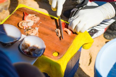 Denizdeki güzel malaga kabuklarını elle temizleyip kesiyor..