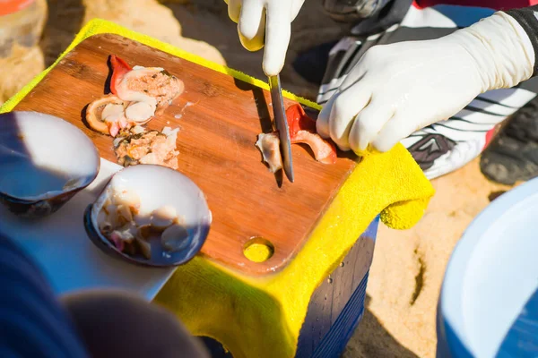 Denizdeki güzel malaga kabuklarını elle temizleyip kesiyor..