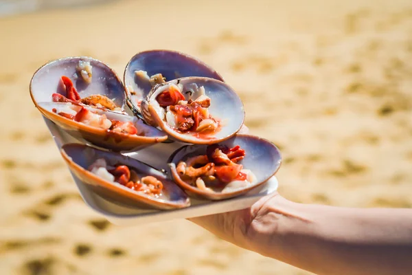 Fine shells from Malaga prepared by hand in the sea, sand background.