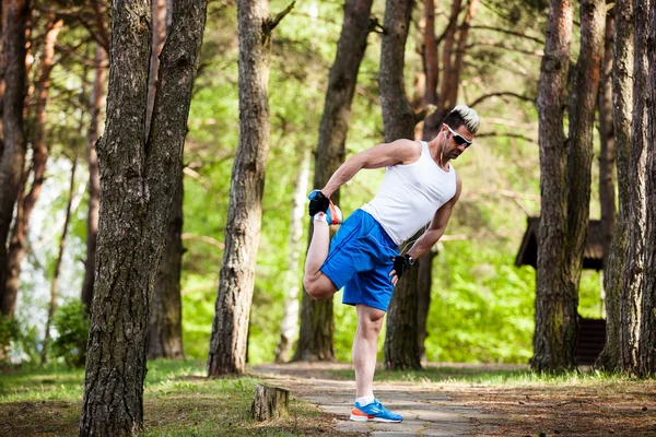 Sportovní muž táhnoucí se v parku - fitness pojmy — Stock fotografie