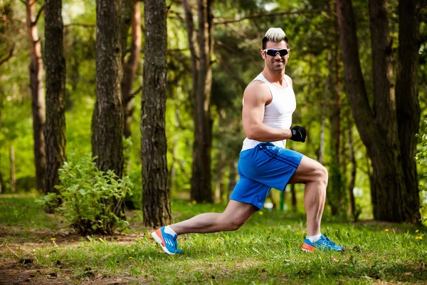 Спортивный человек, растянувшийся в парке - концепции фитнеса — стоковое фото