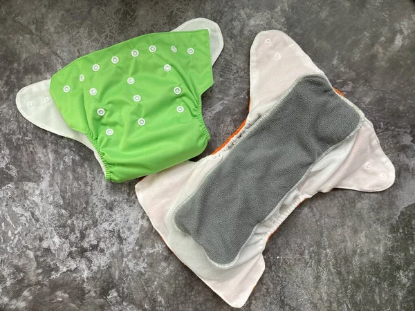 绿色可重复使用的尿布 有婴儿衬里的布尿布 照顾自然和一个婴儿 带有特殊插头的可重复使用尿布 图库照片