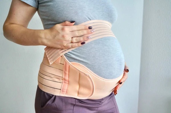 孕妇腰带 后背和腹部支撑 孕妇8 9个月的绷带 第三季节用的特别腰带一个女孩抱着一个怀孕的肚子 图库图片