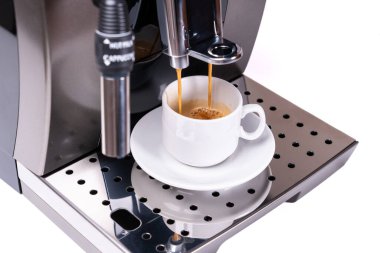 Kahve makinesi taze kahve yapıyor ve fincanın üzerinde gözle görülür buhar var.