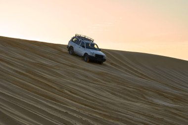Sahara 'da bir ganimet Kum tepelerinde bir yolculuk şafak güneşinin altında ciplerle