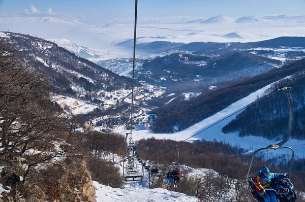 Chairlift on the slope of the ski slope against the background of snowy mountains on a sunny day — Stock Photo, Image