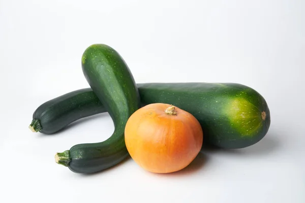 Dos calabacines verdes y una calabaza naranja sobre un fondo blanco —  Fotos de Stock