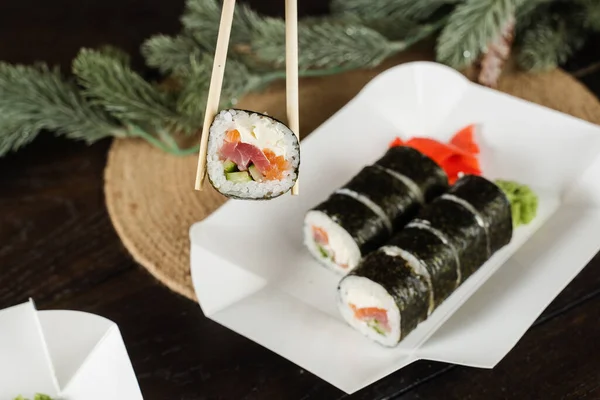 Trzymanie Sushi Rolki Przy Użyciu Pałeczek Opakowaniu Żywności Dostawy Świąteczne — Zdjęcie stockowe