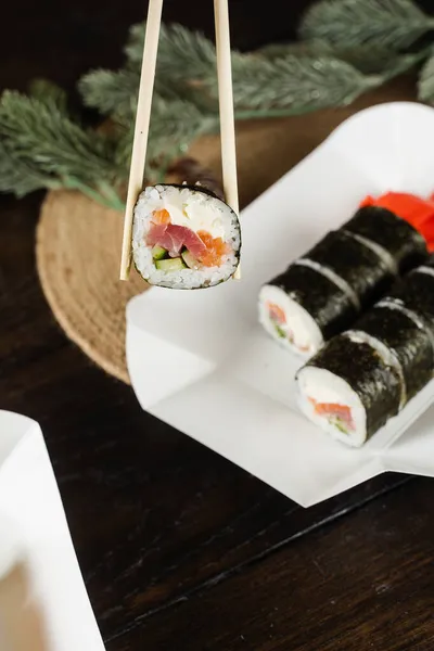 Trzymanie Sushi Rolki Przy Użyciu Pałeczek Opakowaniu Żywności Dostawy Świąteczne — Zdjęcie stockowe