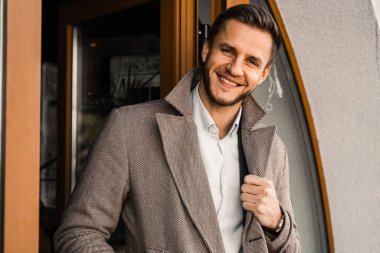 Dışarıda poz veren ceketli yakışıklı sakallı bir iş adamı. Erkek yaşam tarzı