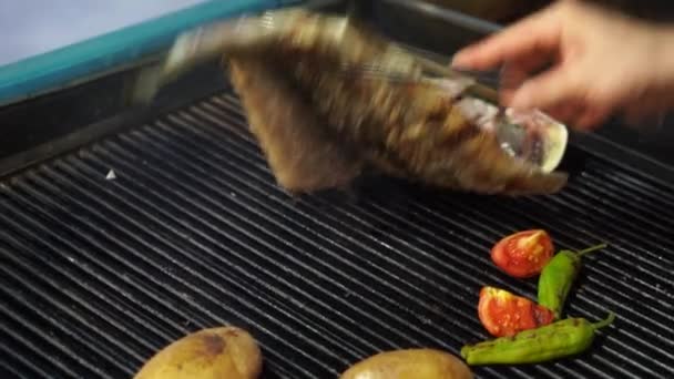 Gotowanie grilla ryby okonia morskiego na grillu. Pieczenie owoców morza z warzywami. 4k wideo. — Wideo stockowe