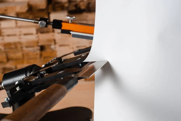 プロのナイフシャープナーの近くに鋭いナイフで紙を切断するプロセスと研磨石のセット — ストック写真