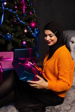 Yeni yıl ağacının yanında hediyeli Müslüman bir kadın. İslam dininin Noel kutlaması