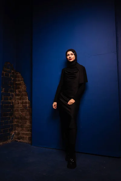 穿着黑色头巾的时尚穆斯林女性正在工作室的蓝色背景上摆姿势 专业高加索模式 — 图库照片