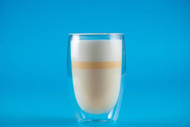 Mavi arka planda sarı kibrit sütlü, olgunlaşmamış mango. Çift cam bardakta kibrit kokteyli.