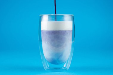 Çift cam bardakta mor goji eşleşmesi. Mavi arkaplanda kibrit kokteyli