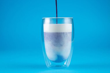 Çift cam bardakta mor goji eşleşmesi. Mavi arkaplanda kibrit kokteyli