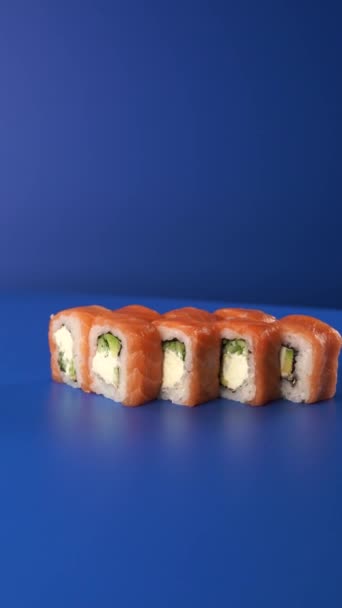 Spinning Philadelphia Roll auf blauem Hintergrund. Sushi 4k Vertical Food Video für soziale Netzwerke. — Stockvideo