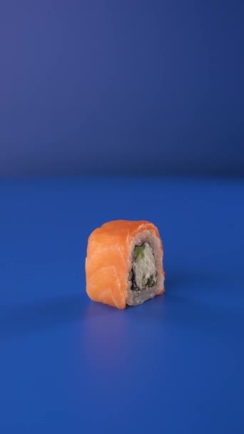 Girando Filadélfia rolar em fundo azul. Sushi 4k vertical food vídeo para redes sociais. — Vídeo de Stock
