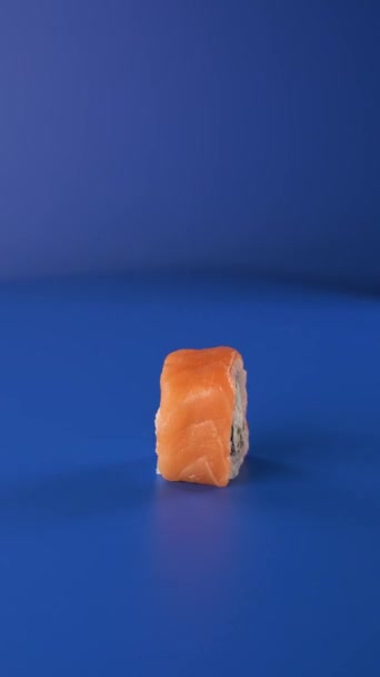Spinning Philadelphia roll on blue background. Sushi 4k vertical food video for social networks. — Stock Video