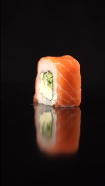 Tournage Philadelphie rouleau sur fond noir. Vidéo alimentaire verticale Sushi 4k pour les réseaux sociaux. — Video