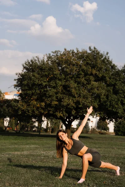 Parktaki yeşil çimlerde antrenman yapan formda bir kız. Açık hava antrenmanı. Aktif genç bayanın spor yaşam tarzı