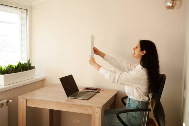 Öğrenci kız sınavı geçti ve yüksek notla seviniyor. Çevrimiçi eğitim ve uzaktan öğrenme. Dizüstü bilgisayarı olan kadın elinde sınav sonuçları olan kağıtlar tutuyor ve seviniyor.