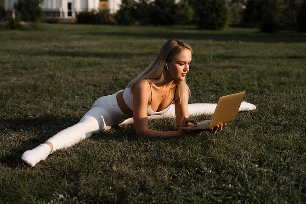 Pasująca Blondynka Laptopem Rozciąga Się Trawie Parku Trening Fitness Online — Zdjęcie stockowe