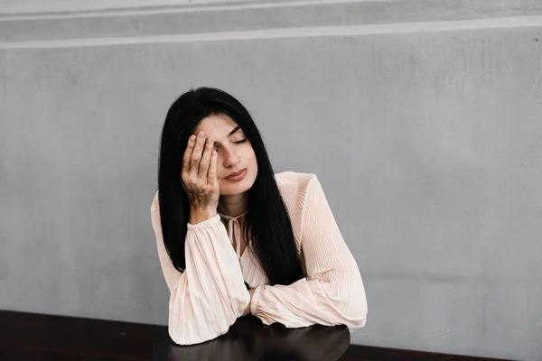 Georgian woman with vitiligo pigmentation patches on hands covers her face with her hands. Lifestyle with skin seasonal diseases