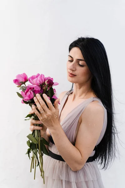 Woman with vitiligo skin pigmentation on the hands holidng bouquet of flowers peonies. Skin seasonal diseases
