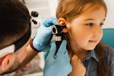 KBB doktoru otoskopla küçük bir kızın kulaklarına bakıyor. Otoskopi. Tedavi çocuk kulak ağrısı