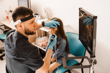 Çocuğun kulak endoskopisi. Otoskopi prosedürü ve otoskop. ENT doktoru otolaringolojist bir kızın kulaklarını tedavi eder.