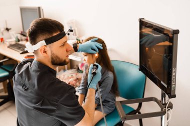 Çocuğun kulak endoskopisi. Otoskopi prosedürü ve otoskop. ENT doktoru otolaringolojist bir kızın kulaklarını tedavi eder.