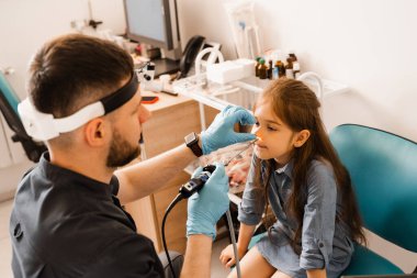 Çocuğun burun endoskopisi. Gergedan bilimi prosedürü. Kulak farlı KBB doktoru, burun hastası çocuğu tedavi ediyor.