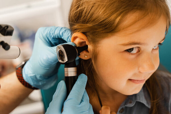 Close-up examination of childs ear with otoscope. Otoscopy. Visit to ENT doctor and consultation